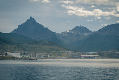 Scenic view of sea and mountains against cloudy sky