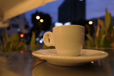 Close-up of coffee cup on table against city skyline 