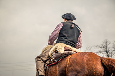Midsection of man riding horse against sky