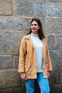 Portrait of smiling young woman standing against wall