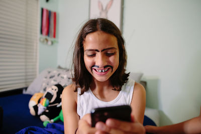 Tween girl laughs while taking a selfie on cellphone of silly makeup