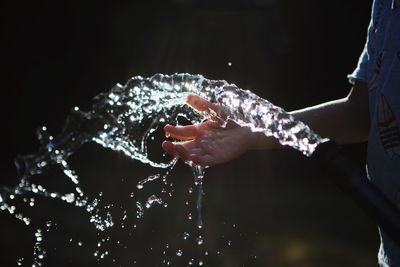 Midsection of boy spraying water with garden hose