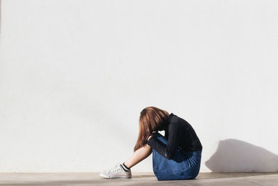 Woman sitting on floor against white background