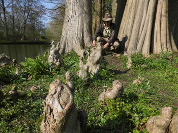 Portrait of man sitting on tree trunk in forest