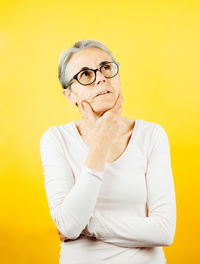 Portrait of young man standing against yellow background