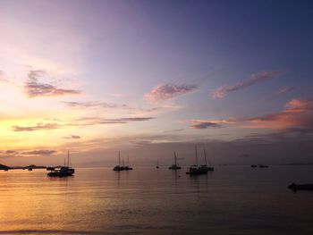 Silhouette sailboats in sea against sky during sunset