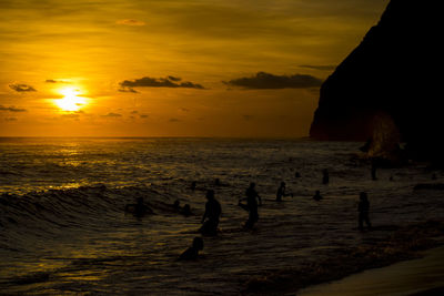 Silhouette people on beach against sky during sunset
