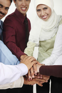 Portrait of colleagues with stacking hands against white background