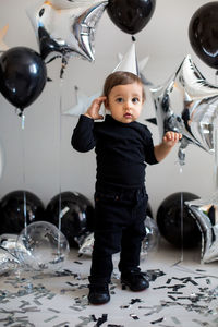 Boy in black clothes on his birthday party with balloon and silver stars