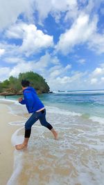 Full length of man running on beach against sky