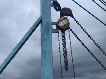 Low angle view of chain hanging on rope against sky