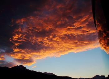 Scenic view of dramatic sky over silhouette mountains during sunset