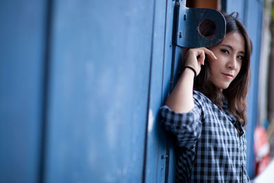 Portrait of young woman leaning on wall