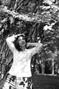 Portrait of young woman standing against trees