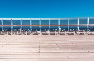 Empty chairs against clear blue sky