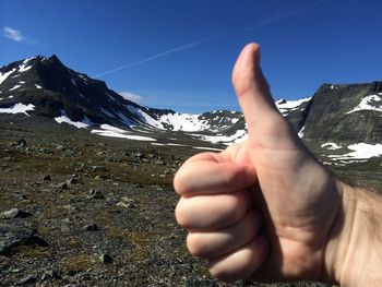 Close-up of hand on mountain against sky