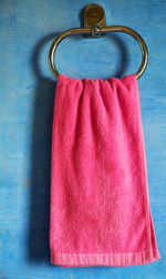 Pink napkin hanging from metal hook mounted on blue wall in bathroom