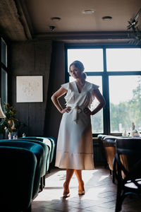 Young woman standing on table in restaurant