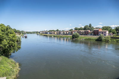 Scenic view of river by houses against clear blue sky