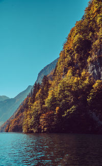 Scenic view of lake by mountains against clear blue sky