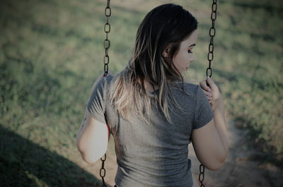 Midsection of woman standing on swing at playground