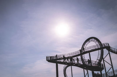 Low angle view of silhouette people on tiger and turtle against sky