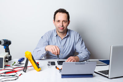 Portrait of young man using mobile phone while sitting on table