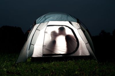 People in tent on field at night