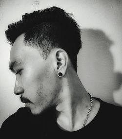 Portrait of young man looking away against wall at home
