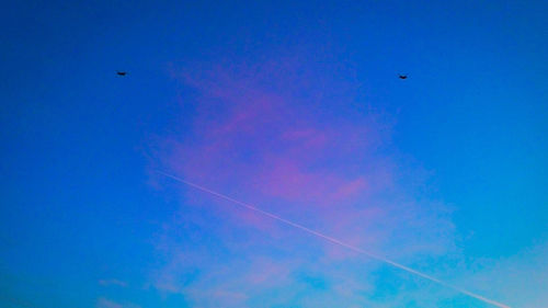 Low angle view of vapor trails against clear blue sky