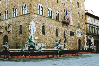 Statue by fountain against building in city