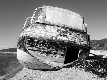 Abandoned boat moored on beach against clear sky