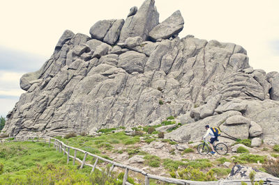 Man cycling on rocky pathway by mountain