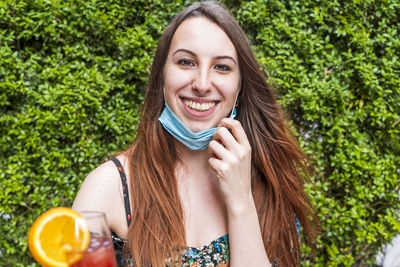 Portrait of smiling young with flu mask holding drink