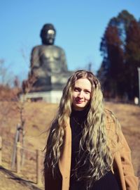 Portrait of beautiful young woman against buddha 