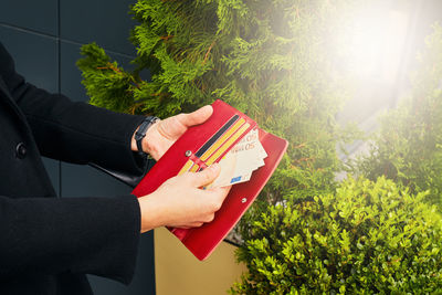 Midsection of person holding book against trees