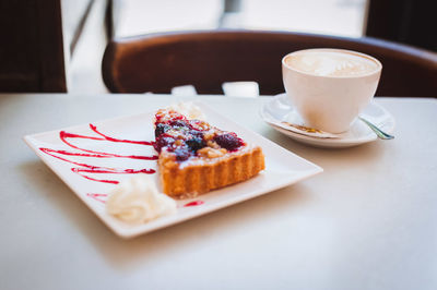 High angle view of pastry with cappuccino served on table