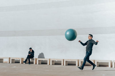 Full length of young man with balloons against wall