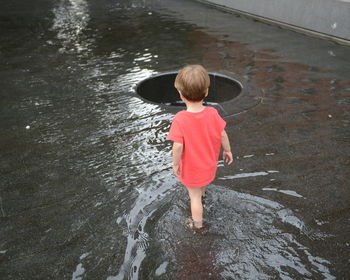 Rear view of boy standing in water