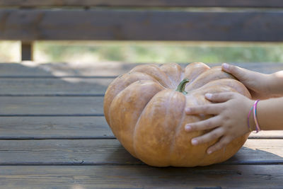 Close-up of hand holding pumpkin on table