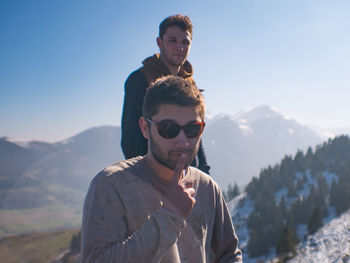 Portrait of friends on mountain against sky