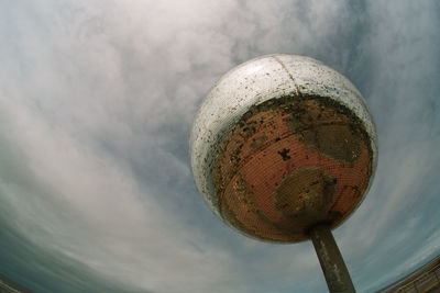 Low angle view of metallic ball against sky