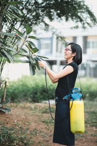 Side view of woman standing against plants