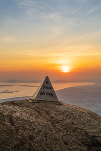 Tilt image of text on land against sky during sunset