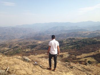 Rear view of man standing on mountain peak