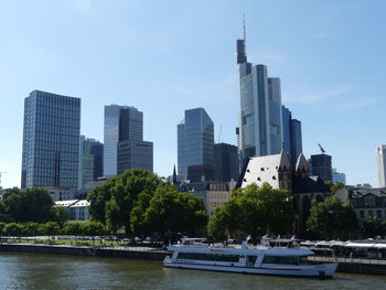 Modern buildings by river against sky in city