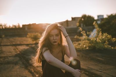 Portrait of beautiful young woman standing against sky