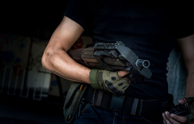 Midsection of army soldier with machine gun and walkie-talkie