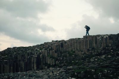 Low angle view of man photographing on rock formations