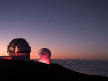 Illuminated built structure on mountain against sky at night